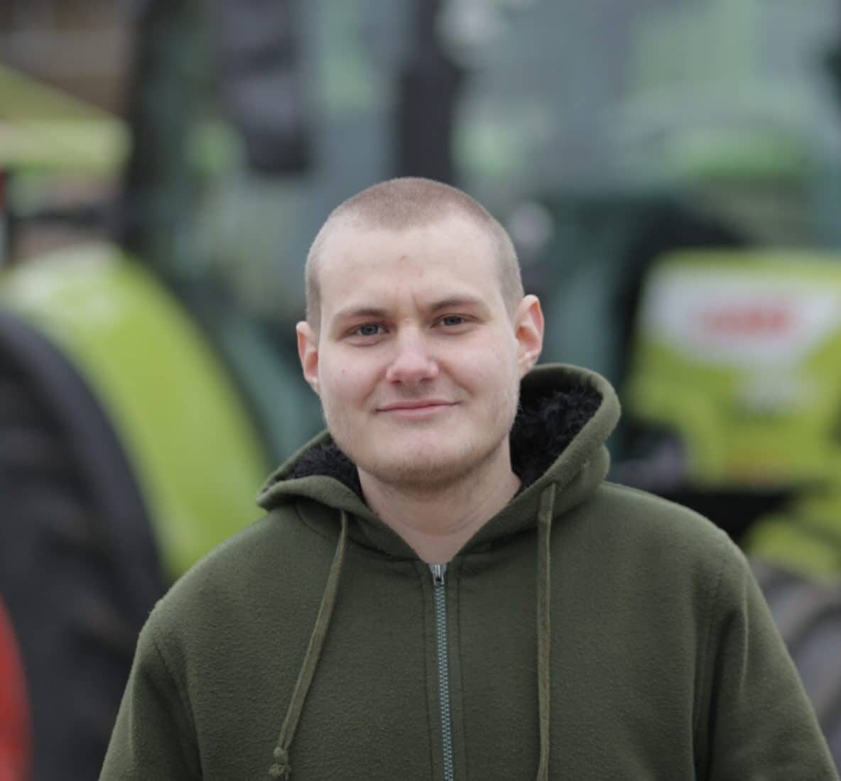 Portrait-Aufnahme von Mattes Reuter, der vor einem Claas-Traktor steht.