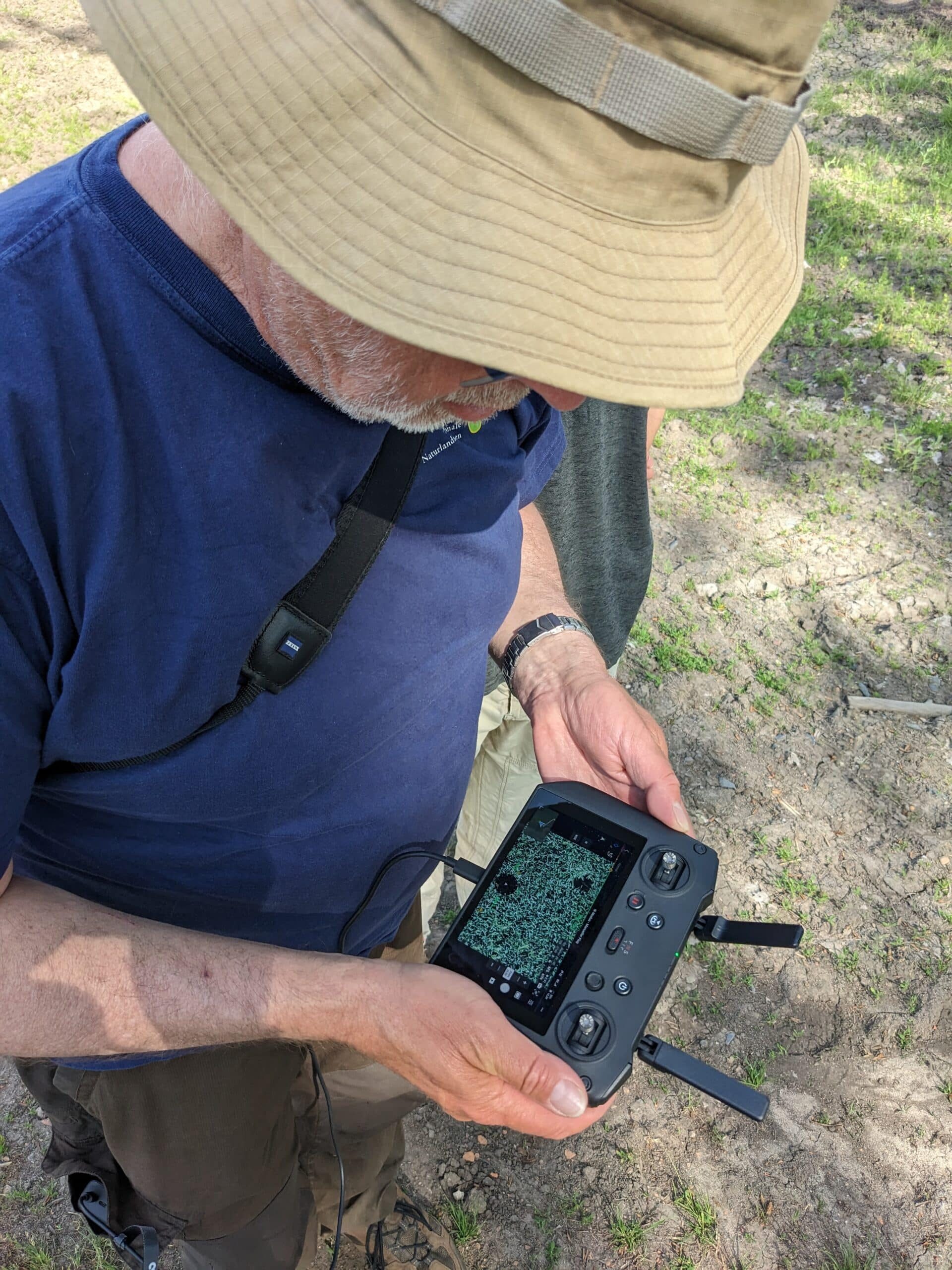 Mann steht im Feld mit einer DJI Fernsteuerung in der Hand