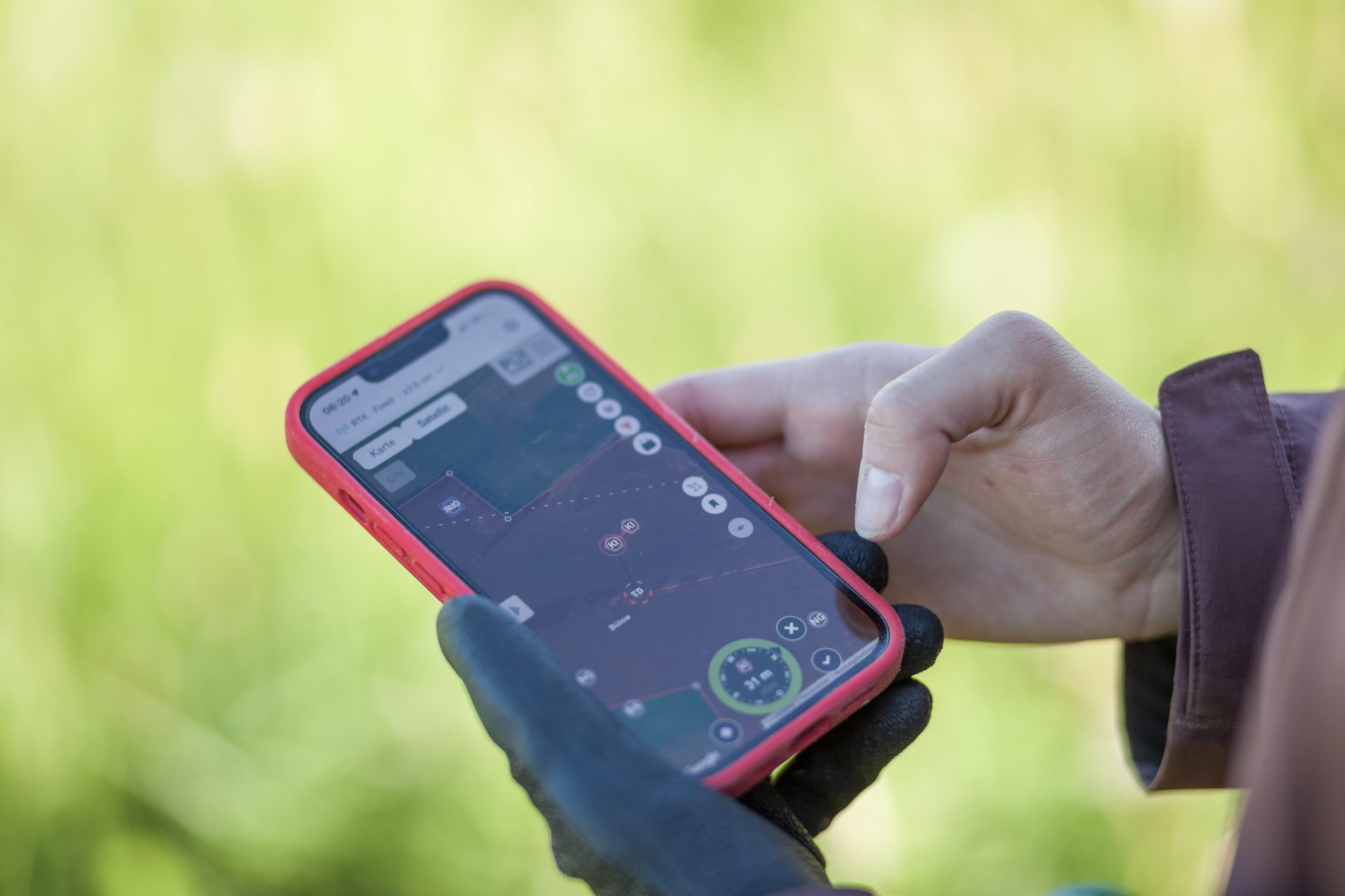 Bild eines Smartphones in den Händen einer Person, auf dem die Navigationsansicht der POIApp geöffnet ist. Die Person befindet sich draußen auf einer Grünfläche. 