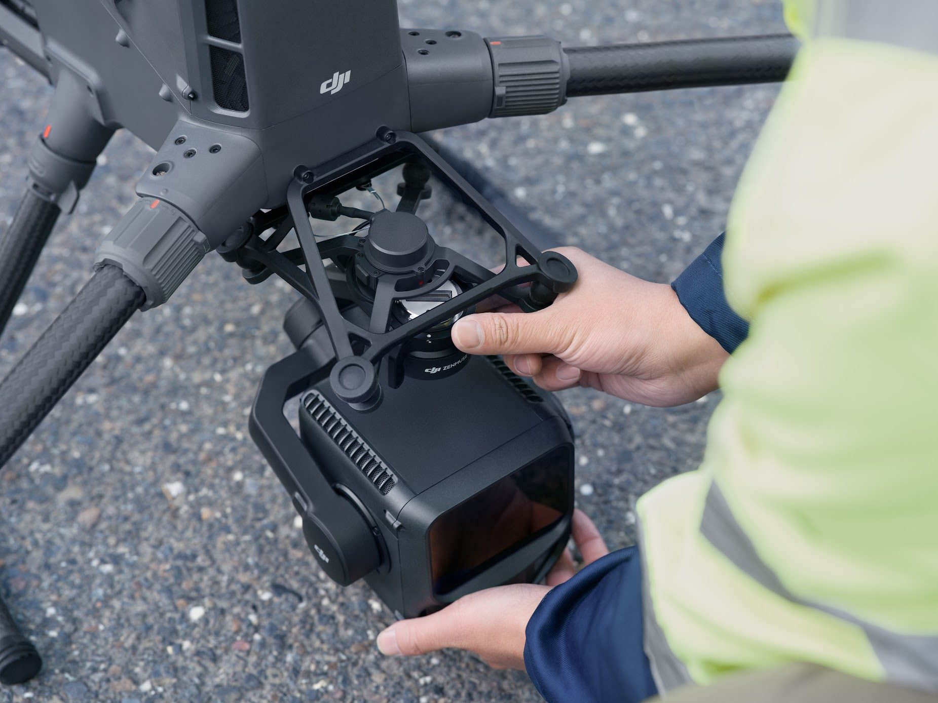 Eine Person in Warnjacke montiert die DJI Zenmuse L3 mit beiden Händen unter einer DJI-Enterprise-Drohne.