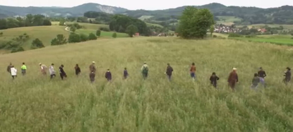 Eine Reihe von Menschen suchen ein Feld zu Fuß nach Rehkitzen ab
